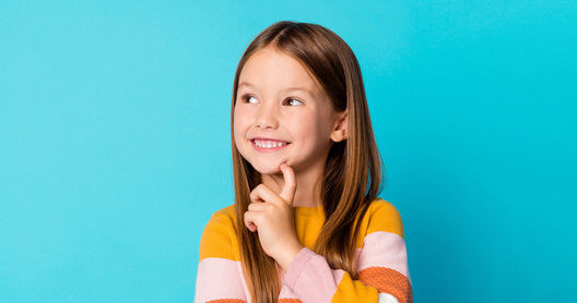 A little girl smiling in front of a blue background after a pediatric appointment