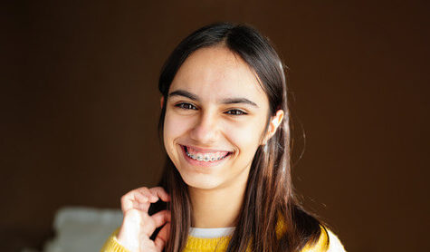 A teenage girl smiling with braces on her teeth after an orthodontic appointment